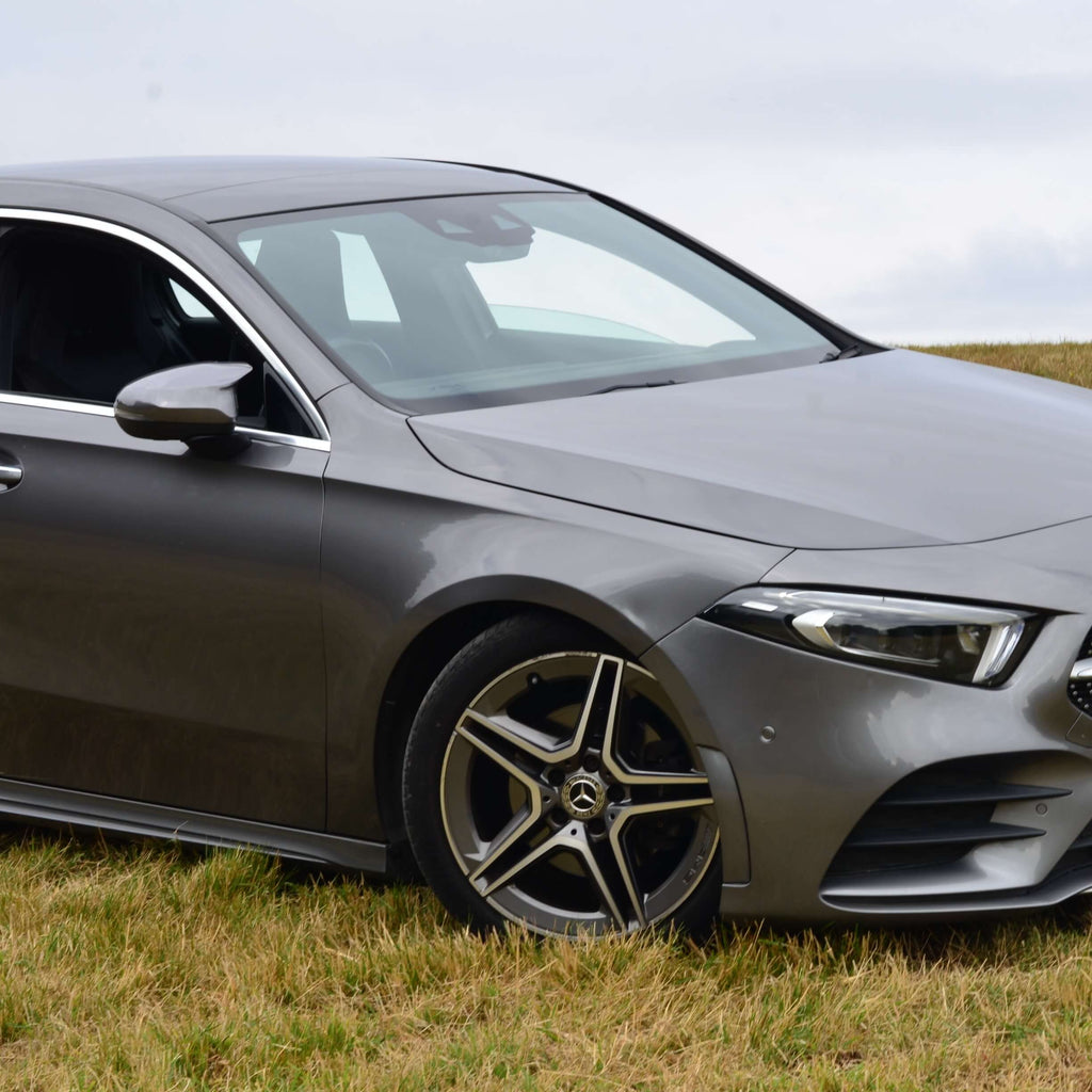 Gray Mercedes-Benz car parked on a grassy field with a cloudy sky.